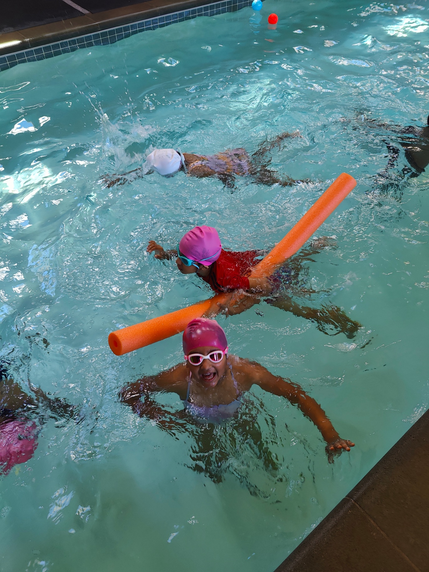 Campers swimming with pool noodles